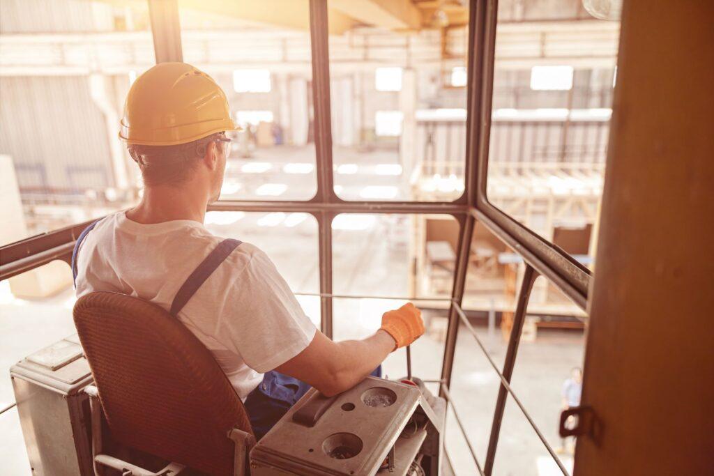 Männlicher Arbeiter sitzt im Führerhaus eines Brückenkrans